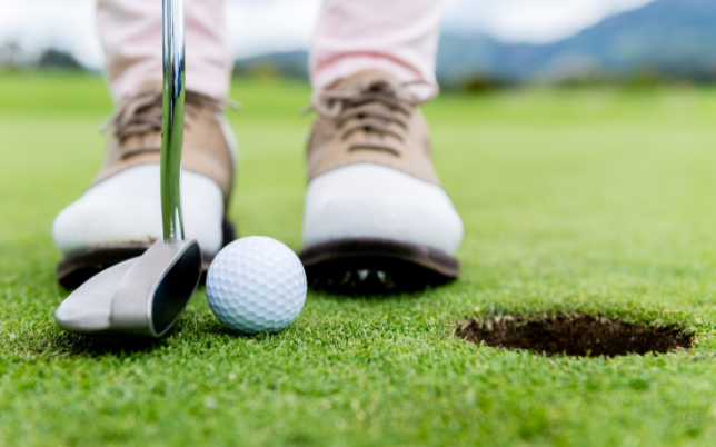 Gros plan sur les pieds d'un golfeur qui s'apprête à frapper la balle de son club