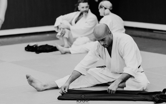 Homme sur le tatami en train de plier son keikogi
