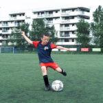 Petit garçon shoote dans le ballon de foot