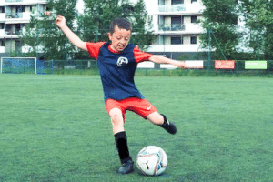 Petit garçon shoote dans le ballon de foot