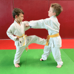 Deux petits garçons ceintures jaunes qui se font une prise lors d'un cours de judo