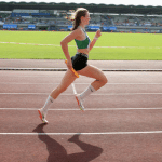 Jeune femme qui court sure une piste d'athlétisme, relais à la main