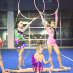 4 jeunes filles en tenue de GRS posant avec ballon, cerceaux et massues