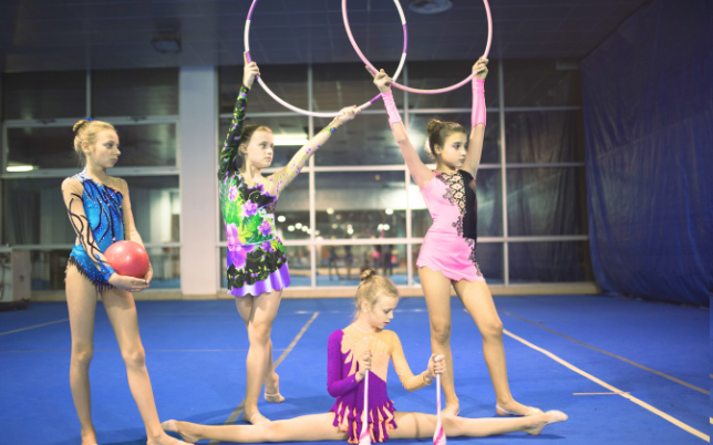 4 jeunes filles en tenue de GRS posant avec ballon, cerceaux et massues