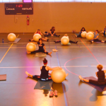Groupe de femmes au sol dans un gymnase, maniant des ballons de yoga