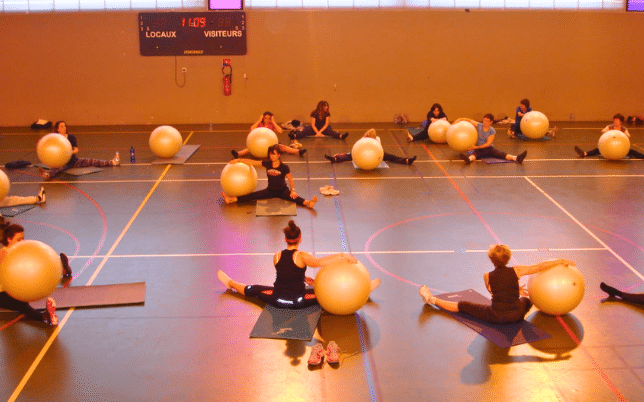 Groupe de femmes au sol dans un gymnase, maniant des ballons de yoga